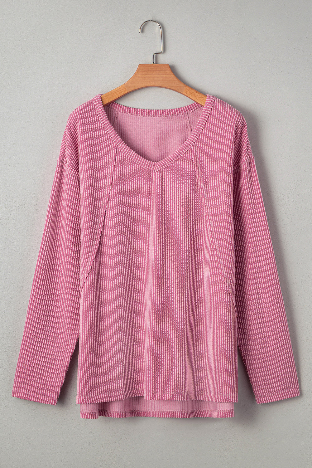 Modern Grace pink ribbed long sleeve top with exposed seams and loose fit, featuring a textured fabric design.