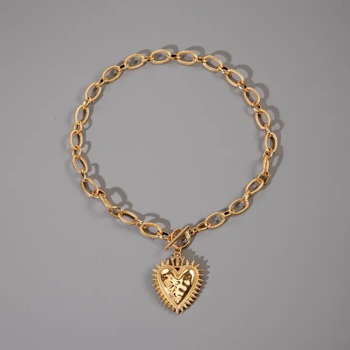 Gold spiked heart chunky chain toggle necklace by JOSSLYN, featuring bold spikes and a heart-shaped pendant on a thick chain.
