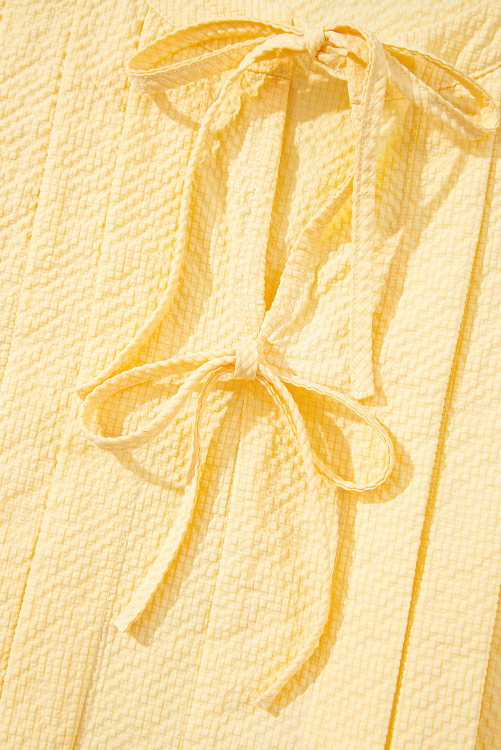 Yellow cream bow tie tank top by Modern Grace featuring notched neck and pleated design, made of 100% polyester.