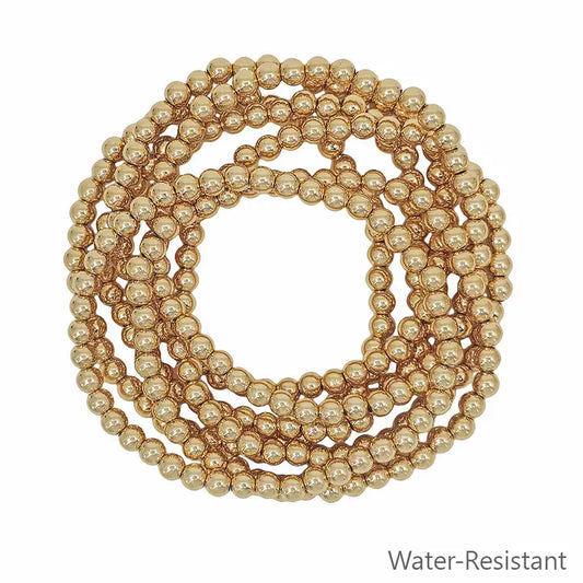 Water-resistant set of 7 gold textured 5mm beaded stretch bracelets from What's Hot jewelry collection, displayed in a stylish arrangement.