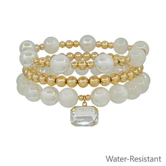 White beaded and gold stretch bracelets set with square crystal charms, stylish jewelry by What's Hot.