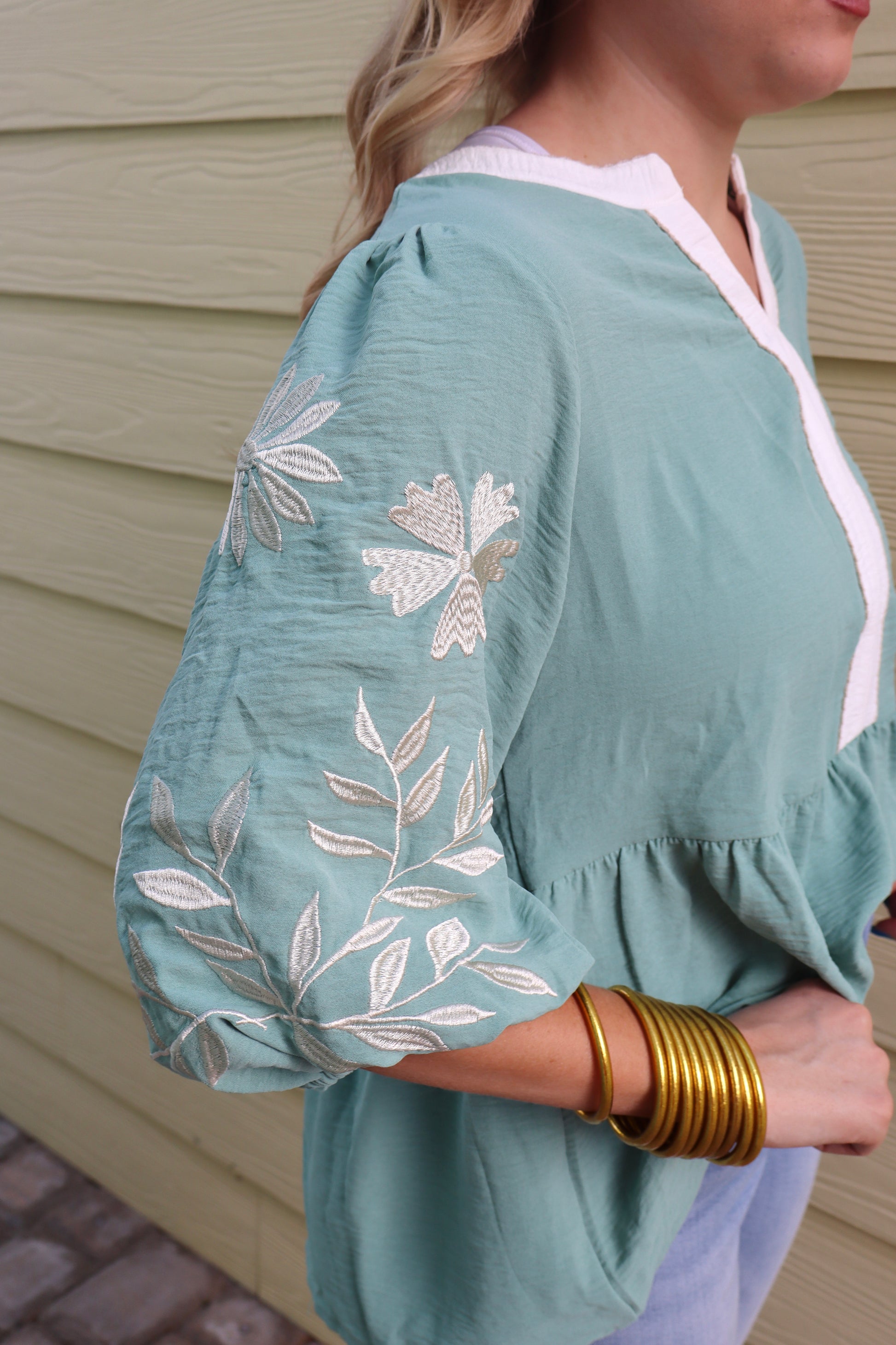 Sage green patchwork babydoll blouse with V-neck, embroidered details, and puff sleeves by Modern Grace.