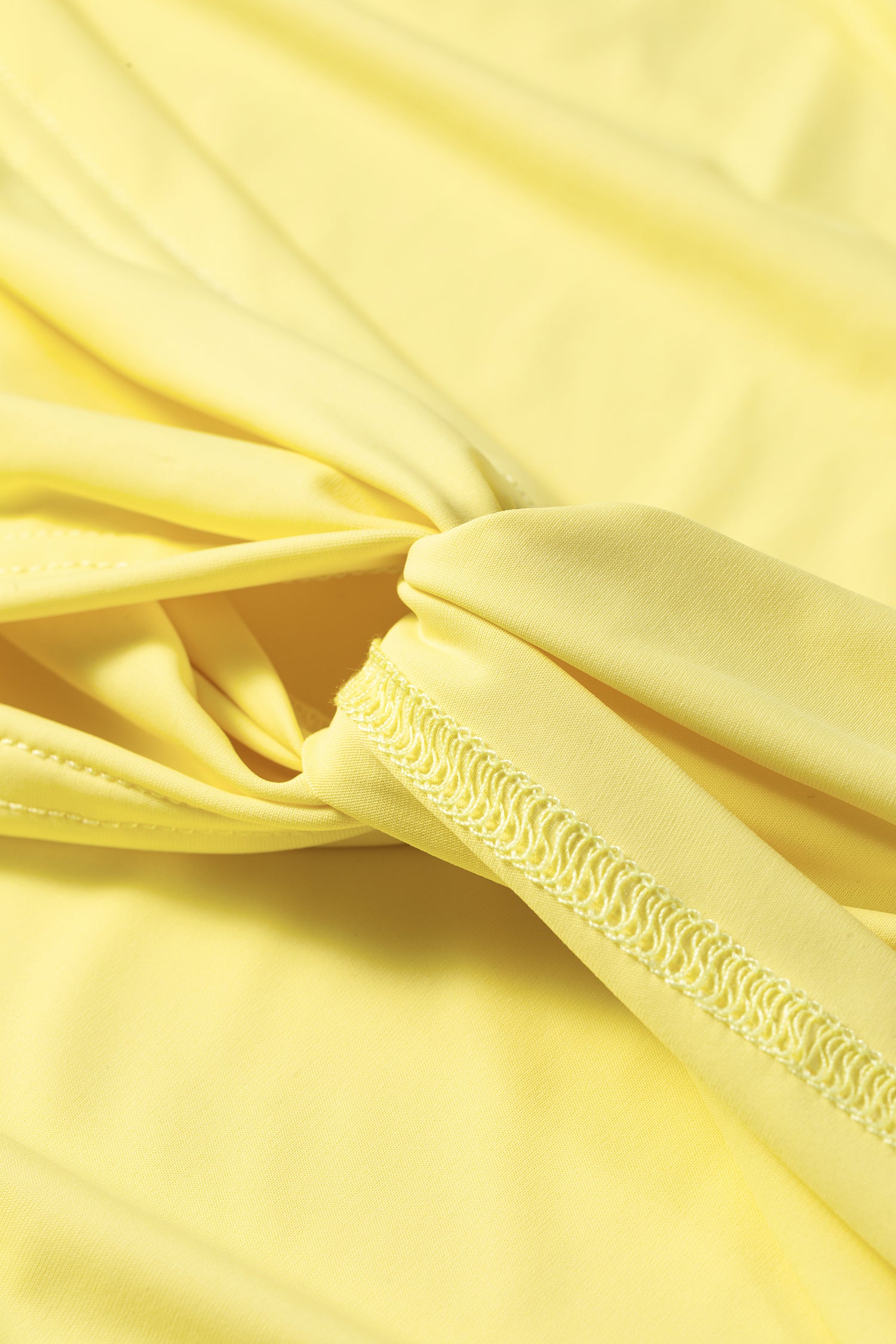 Close-up of pale yellow fabric with a gathered knot and visible stitched edge detail.