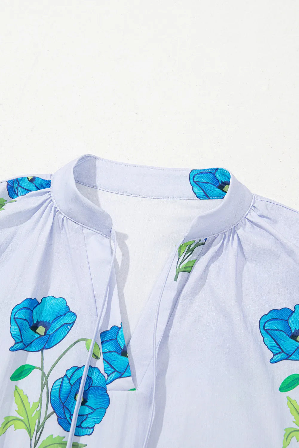 Sky blue floral print tie split neck blouse with short puff sleeves by Modern Grace, featuring a stylish and feminine design.