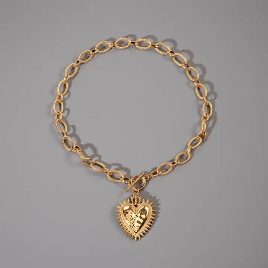 Gold spiked heart chunky chain toggle necklace by JOSSLYN, featuring bold spikes and a heart-shaped pendant on a thick chain.