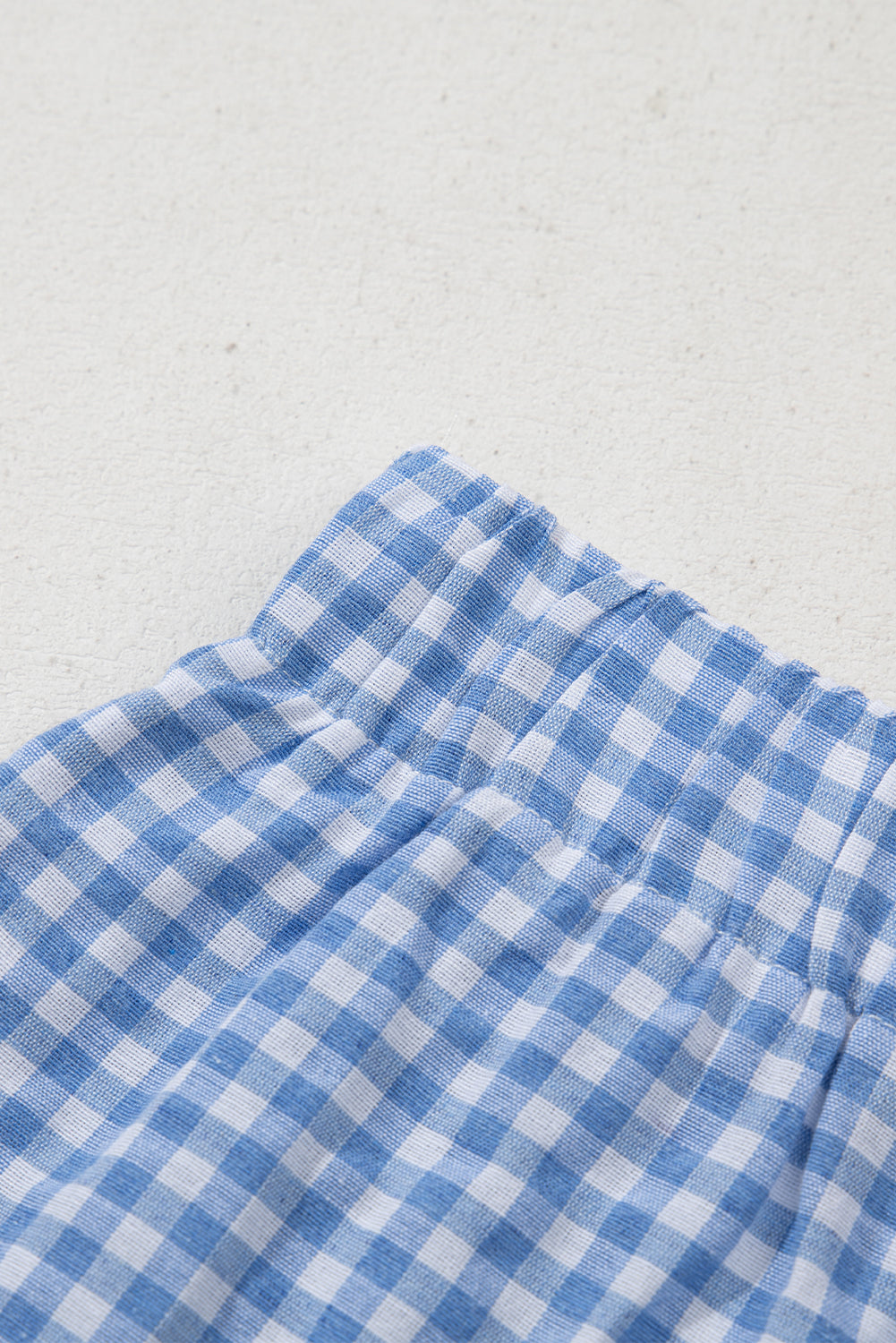 Blue gingham boxer shorts by Modern Grace, casual bottoms made of lightweight polyester, shown laid flat.