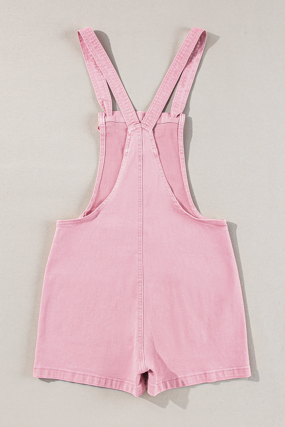 Pink solid color denim romper with knot straps and pockets by Modern Grace, featuring a casual, stylish design.