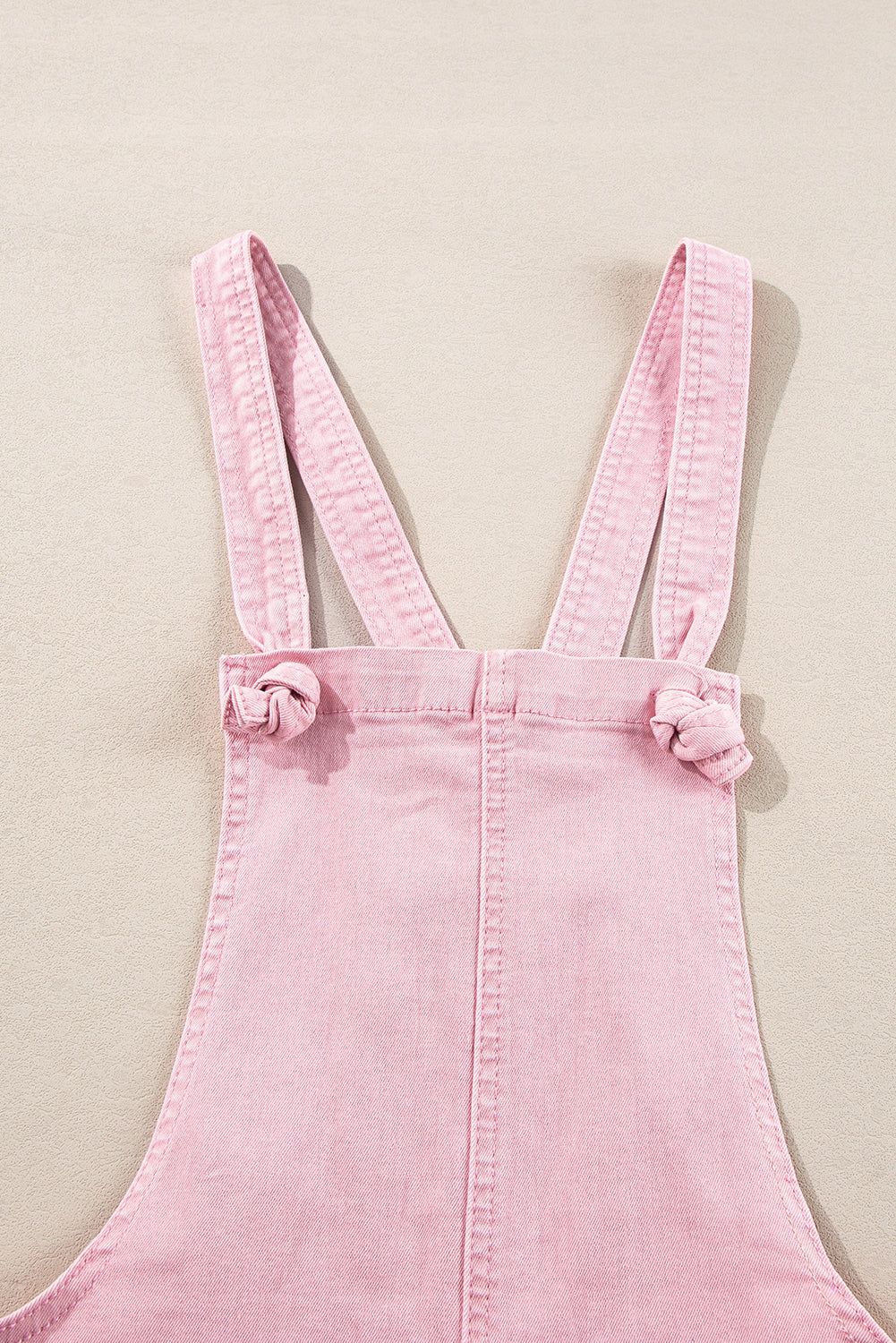 Pink solid color denim romper with knot straps and pockets by Modern Grace, featuring a casual fit and stylish design.