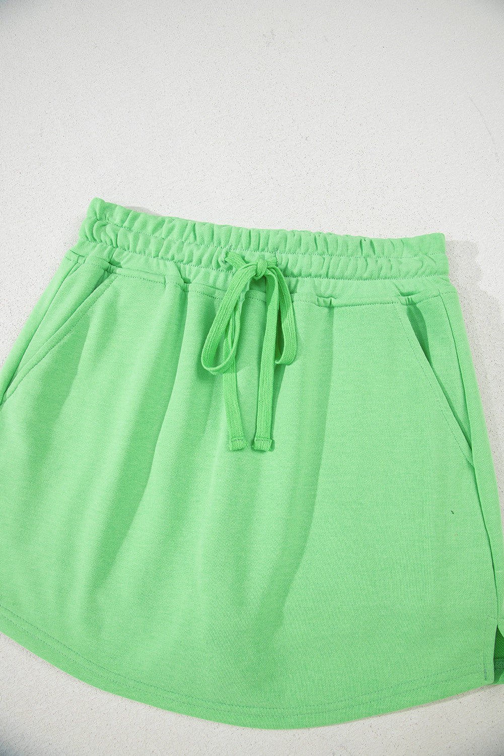 Light green French terry mini skort with drawstring, pockets, and brand logo from Modern Grace, casual bottoms for women.