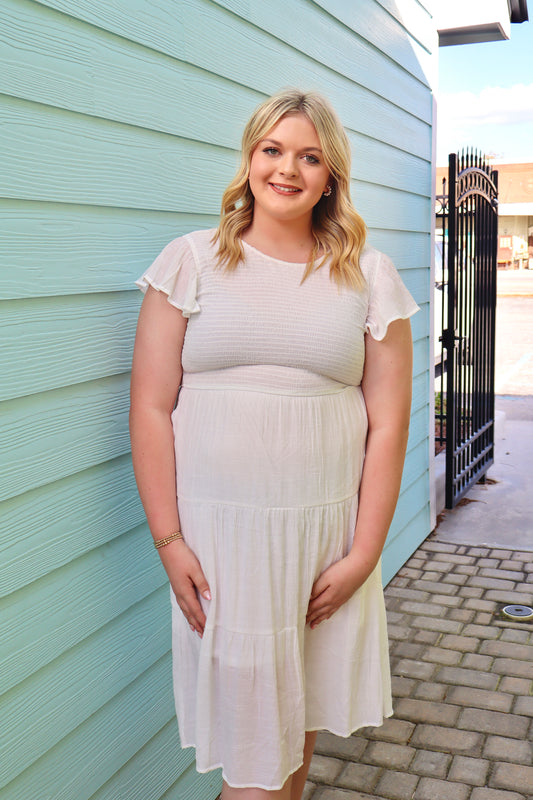 White smocked midi dress by Modern Grace featuring a fitted bodice and flowing skirt, perfect for casual or semi-formal occasions.