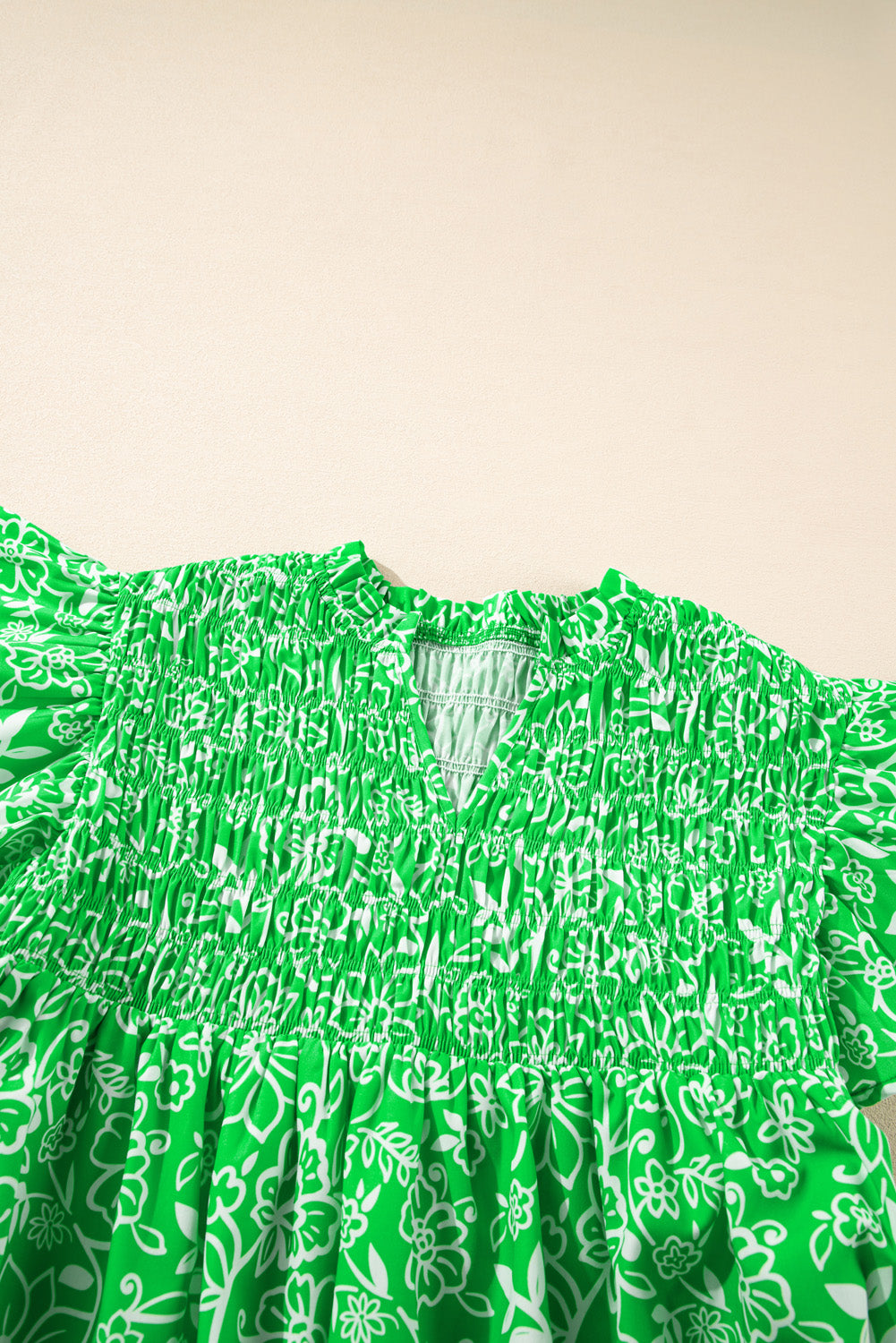 Green floral plus size blouse by Modern Grace with flutter sleeves, shirred details, and a notched neckline.