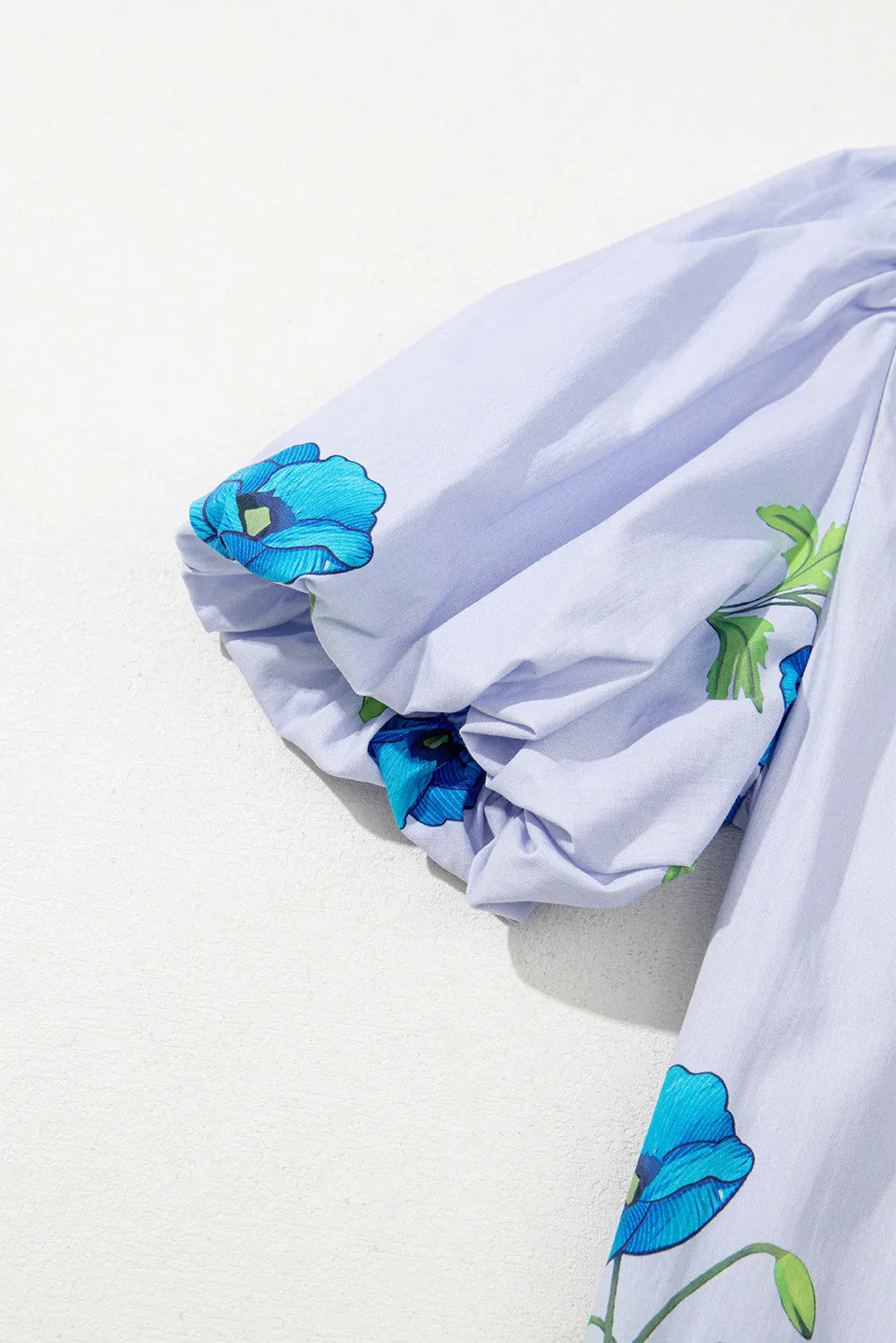 Sky blue floral print blouse by Modern Grace featuring a tie, split neck, and short puff sleeves.