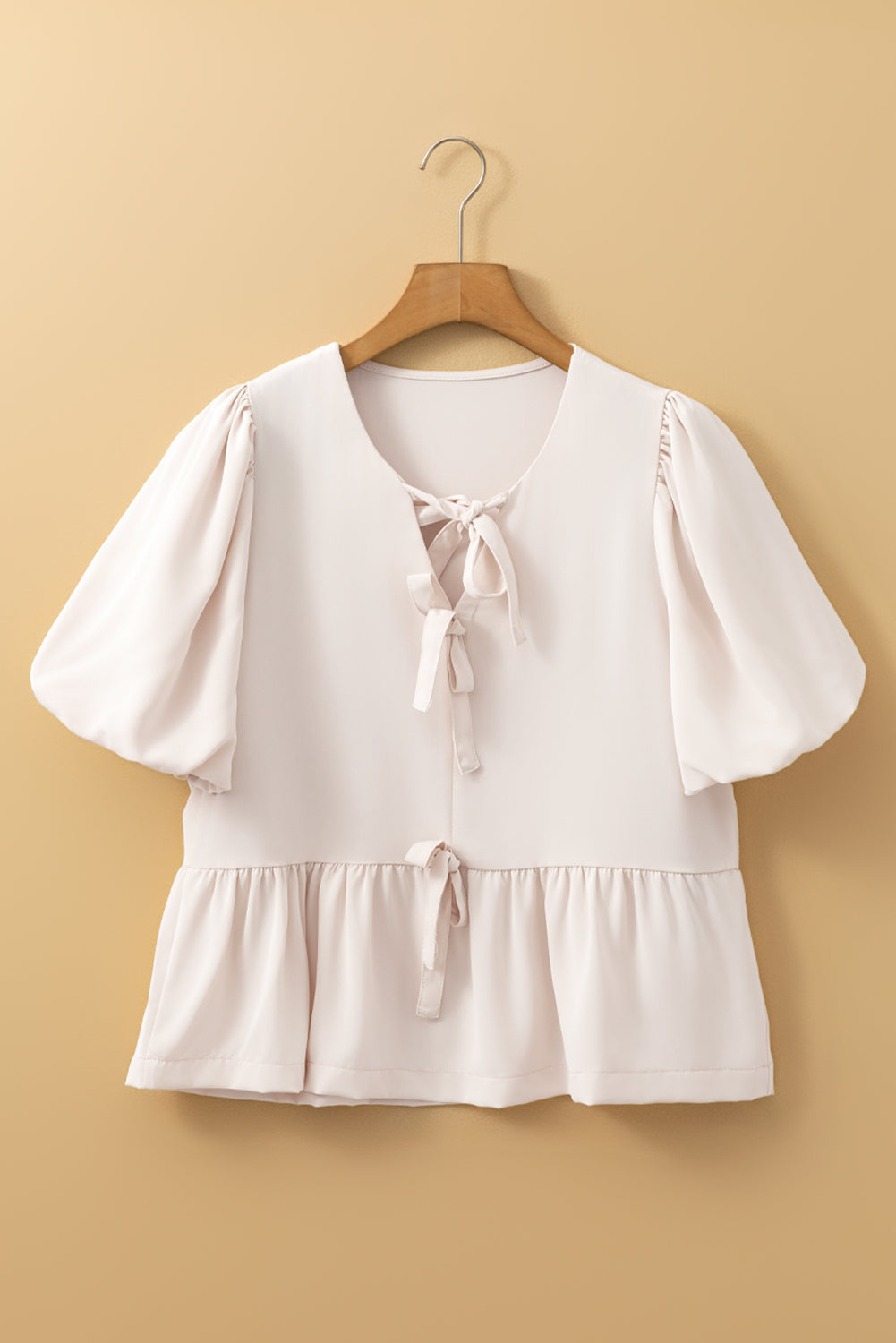 Off White Modern Grace blouse with bow tie, short puff sleeves, and ruffle hem, featuring a stylish, lightweight polyester design.