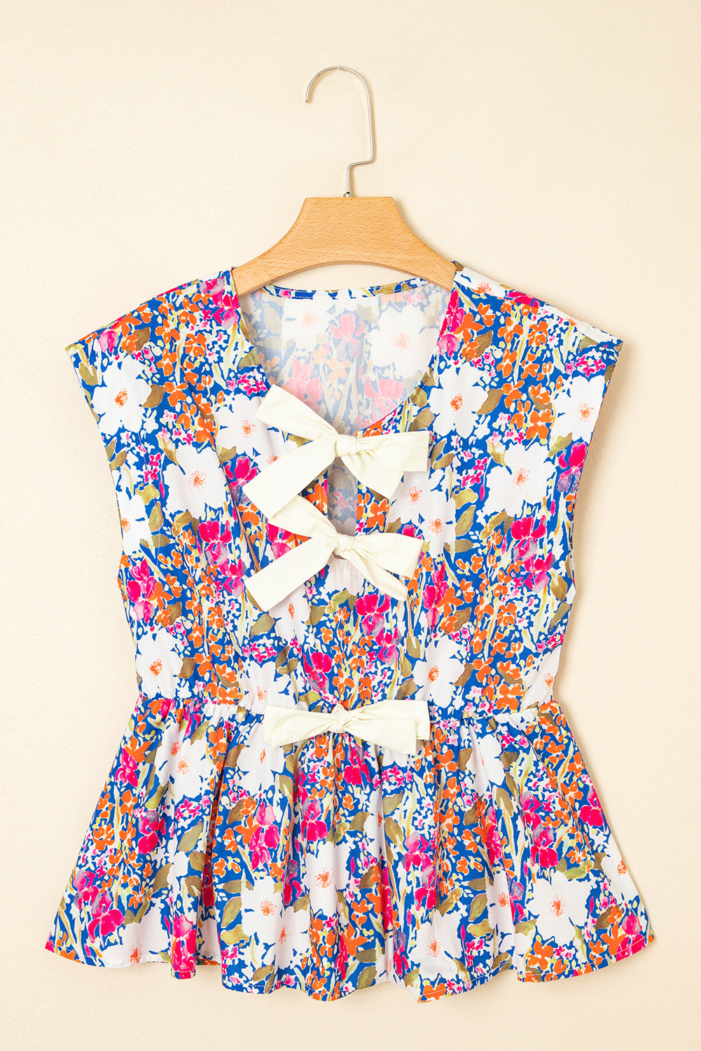 Modern Grace floral print sleeveless peplum blouse with bow applique, slit sleeves, and feminine design.