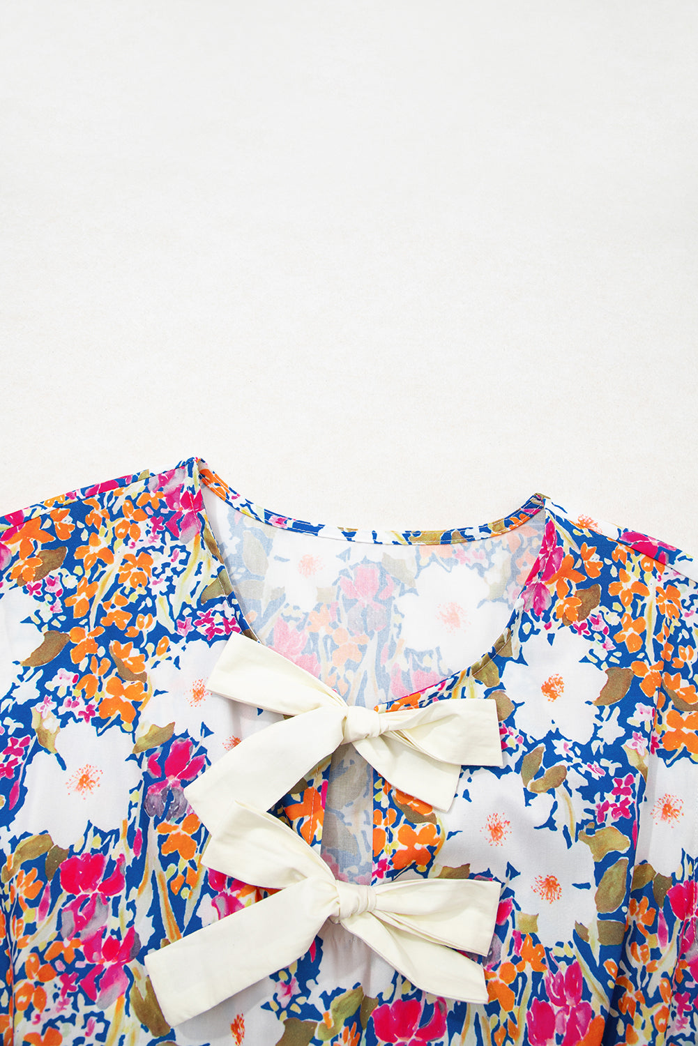 Modern Grace floral print sleeveless peplum blouse with bow applique and slit sleeves, featuring a feminine design.