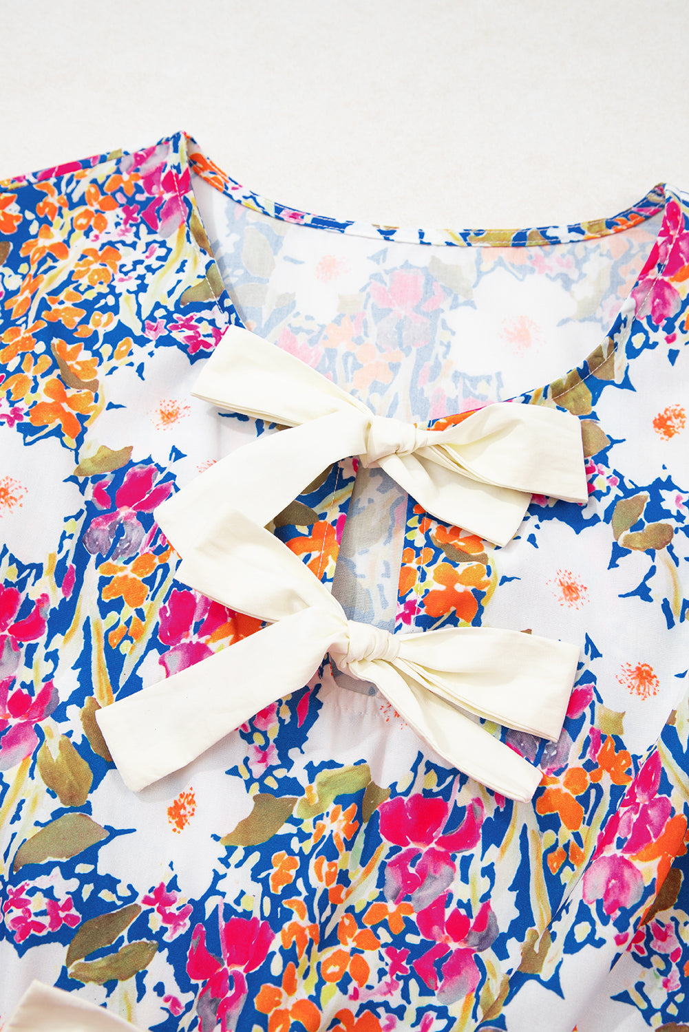 Modern Grace floral print bow applique sleeveless peplum blouse with slit sleeves, made of 100% polyester, online exclusive.