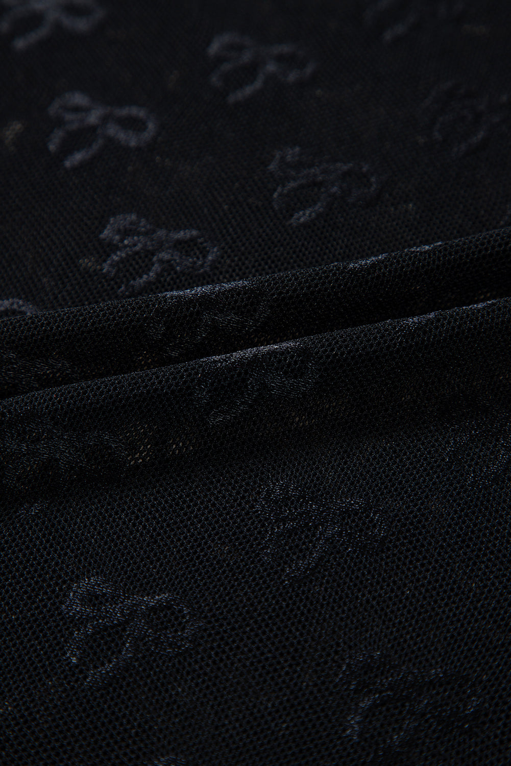Black mesh long sleeve top with bow pattern by Modern Grace, featuring a fitted design and subtle see-through fabric.