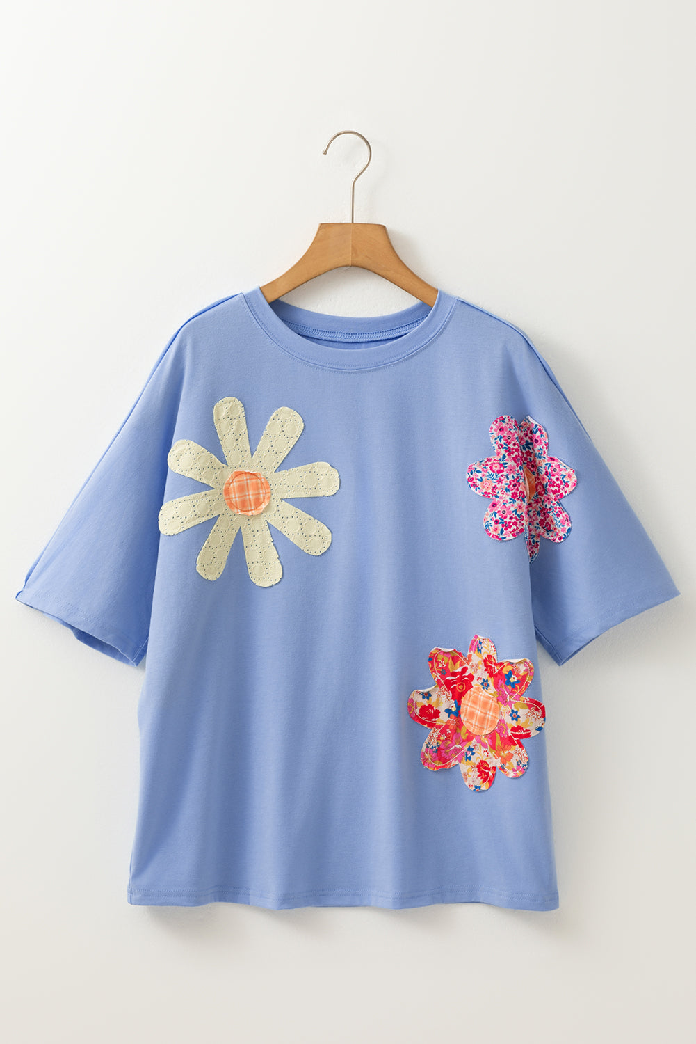Sky blue loose crew neck tee by Modern Grace with flower patches and exposed stitching, featuring a casual, relaxed fit.