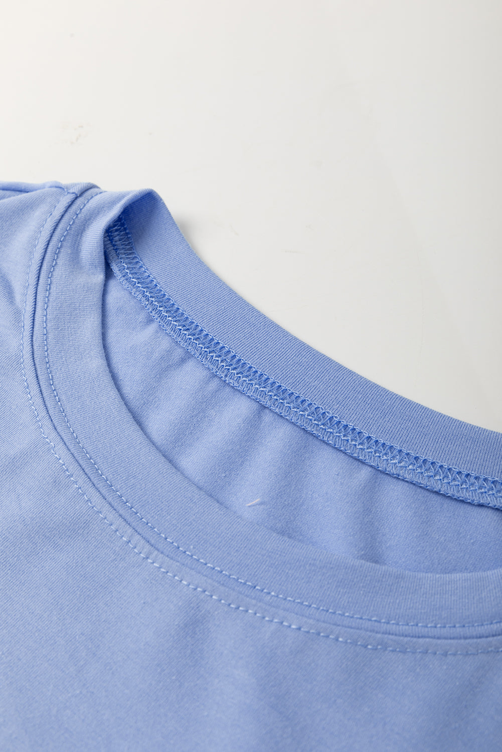 Sky blue flower patched loose crew neck tee by Modern Grace with exposed stitching, polyester-cotton blend, stylish and comfortable.