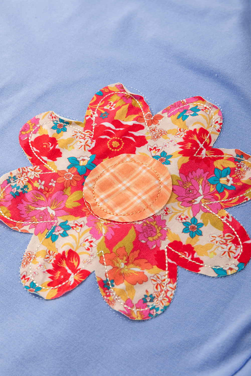 Sky blue loose crew neck tee by Modern Grace featuring flower patches, exposed stitching, and trim details.