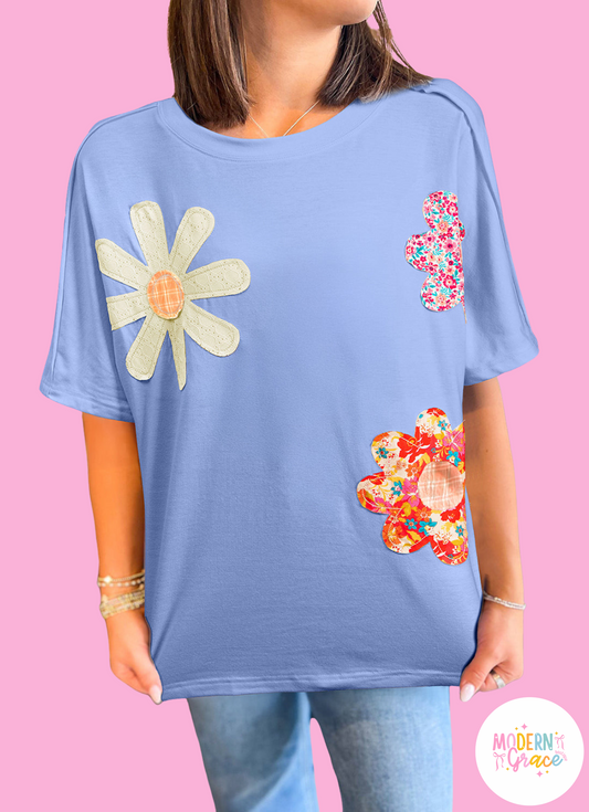 Sky blue floral patched loose crew neck tee by Modern Grace featuring exposed stitching and trim, casual top for women.